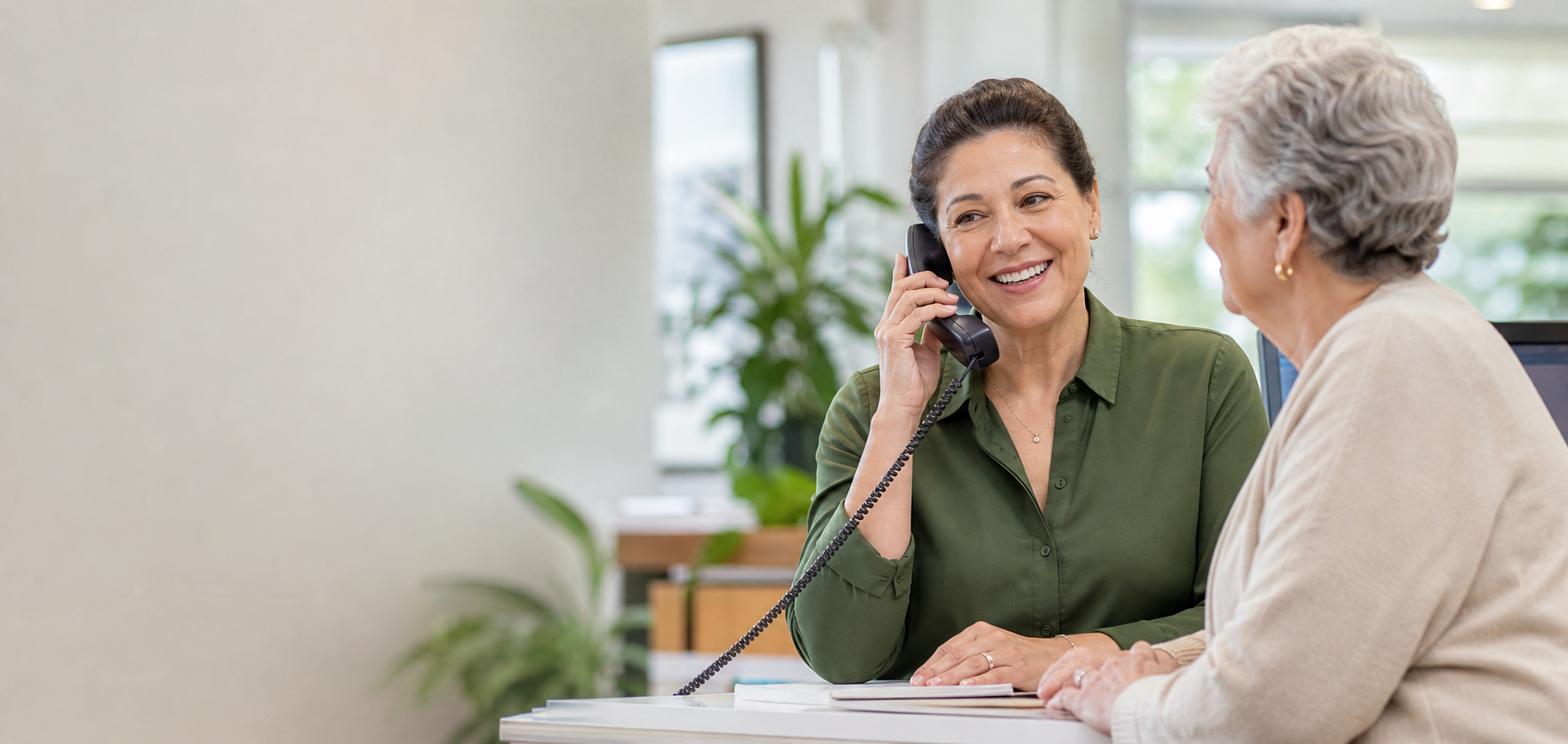 A friendly staff member speaking on the phone while assisting an older woman